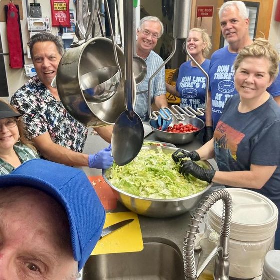 Members prepping a giant bowl of salad